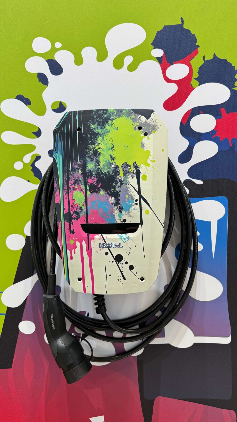 Eine Graffiti_Wallbox auf dem Kostal Messestand in München auf einem bunten Hintergrund.